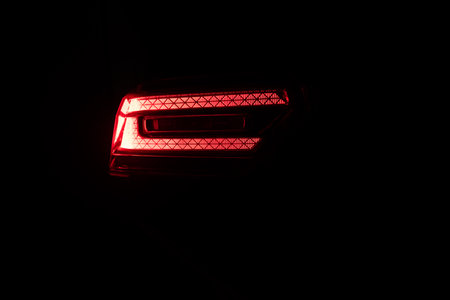 Car back lights shining. Close up detail on one of the LED red taillight modern luxury car. Exterior detail automobile. Tail light car. Detail on the rear light of a carの写真素材