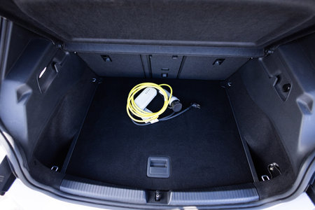 Electric car charger in car trunk. Electric car. Car trunk with charging cables. Modern car...