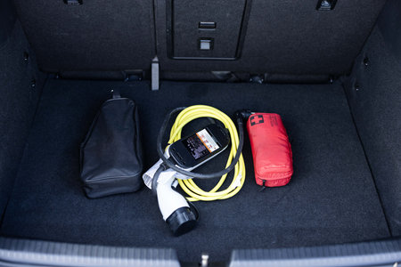 Electric car charger in car trunk. Electric car. Car trunk with charging cables. Modern car interior, car trunk. Portable in-cable charging box for electric car charging lying in a car trunk.の写真素材