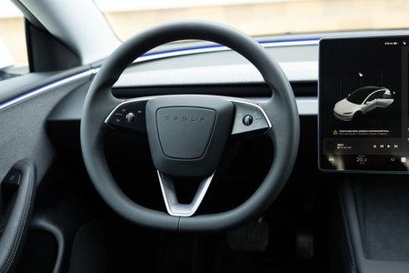 Lviv, Ukraine - March 23, 2024: Steering wheel, Tesla electric car model 3 Interior, Highland light strip, cockpit modern EV technologies car manufacturing, eco-friendly engines.のeditorial素材