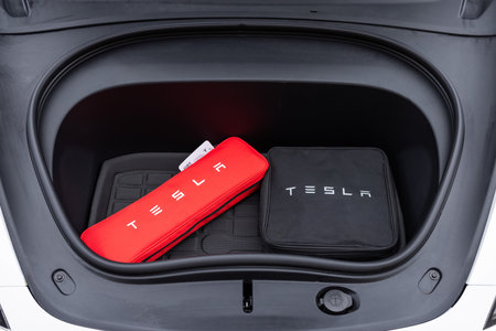 Lviv, Ukraine - March 23, 2024: The so-called trunk of a Tesla Model 3 Highland Here you can see that it is quite small, but still fits a lot. Open trunk in front of a white car.のeditorial素材