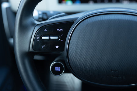 Close-up view of car interior. View of steering wheel of car control music. Volume button of car radio on steering wheel. Turns up the volume of the music in the car. Drive modeの写真素材
