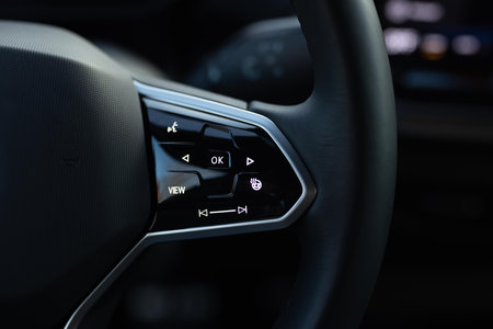 Heated steering wheel control buttons with blurred dashboard in car interior. Heated steering wheel...