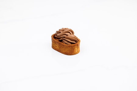 Tartlet with caramelized nuts isolated on white. Tasty dessert. Caramel tartlet, caramelized peanuts, salted caramel, chocolate ganache. Dessert of dough, nut tartlets covered with a layer of caramelの写真素材