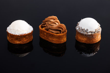 Caramel tartlet with caramelized peanuts, salted caramel, chocolate ganache. Berry tart gluten-free biscuit, vanilla mousse, glaze. Coconut tartlet with sponge cake, pineapple, coconut mousse, icingの写真素材