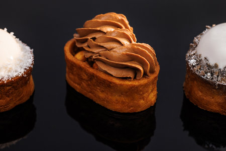 Caramel tartlet with caramelized peanuts, salted caramel, chocolate ganache. Berry tart gluten-free biscuit, vanilla mousse, glaze. Coconut tartlet with sponge cake, pineapple, coconut mousse, icingの写真素材