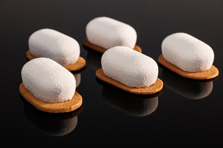 Creme brulee mousse cakes. Vanilla sable, chocolate sponge, coffee baileys icing. Creme brulee cakes with vanilla sable and chocolate sponge on a black background. Tasty sweet dessertの写真素材
