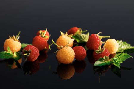 Sweet ripe fresh delicious raspberry, summer berry, organic food, vitamins. Raspberry with leaves. Fresh red ripe raspberries. Delicious fresh raspberries on black backgroundの写真素材