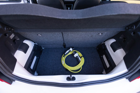 Electric car charger in car trunk. Trunk with charging cables. Modern interior. Portable in-cable charging box for electric car charging lying in car trunk.の写真素材