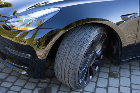 Close up winter tires on a road. Driving car with winter tire wheel on road. Detail of car tires in...