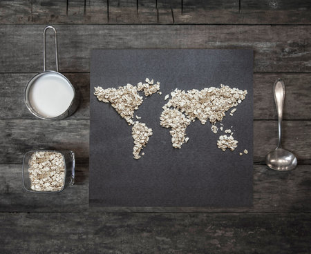 Oatmeal on a rustic wooden table in the shape of a world map. View from above.