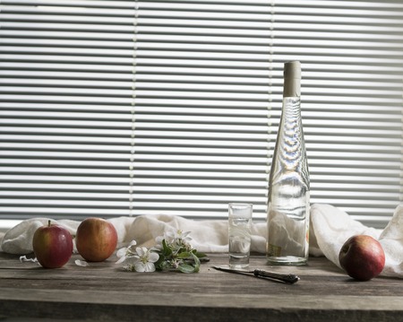 bottle of Calvados, apples, antique silver on a wooden tableの写真素材