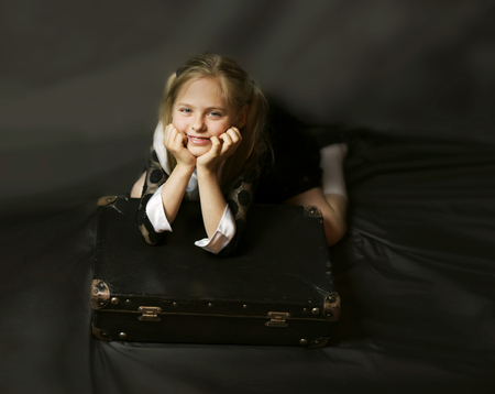 beautiful blond girl and an old suitcase on a dark background, retro styleの写真素材