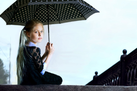 beautiful blond girl with an umbrella on the steps of the waterfrontの写真素材