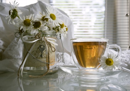 cup of tea, lace sundress, and a bouquet of daisies on a background of the summer window.の写真素材