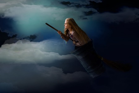 girl witch flies in a mortar with a broom in the night skyの写真素材