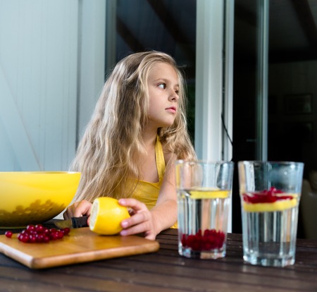 Pretty girl is preparing berry drink from a lemon and red currantの写真素材