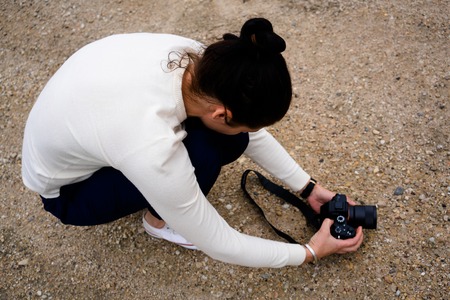 young female photographer is doing landscape photographyの写真素材