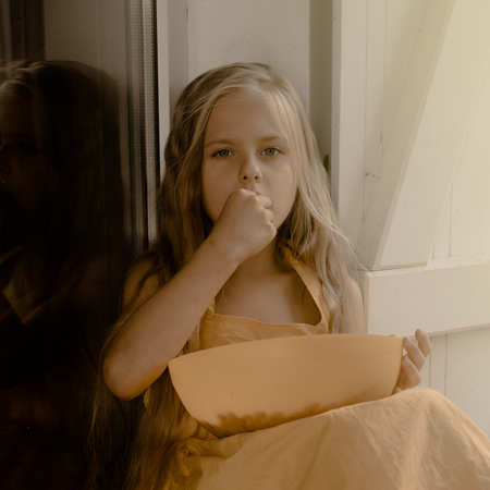 vintage. girl sitting at the terrace window and eats berries in a yellow dress.の写真素材