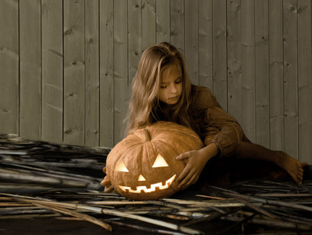 vintage. retro style. Halloween. cute little girl sitting next to a pumpkin glowingの写真素材