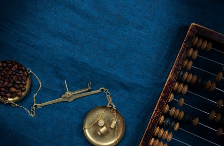 scales with weights and coffee beans and old scores on a blue clothの写真素材