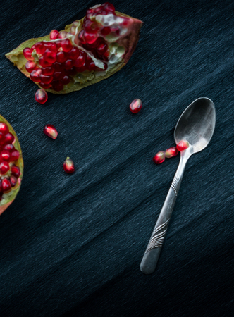 still life. silver spoon, cut pomegranate and garnet grainsの写真素材