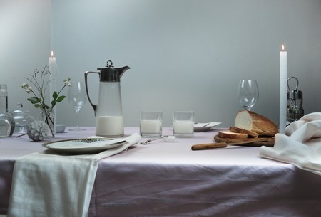 table setting. table with tablecloth, milk in the old Countess, bread, flowers in a vase, candleの写真素材