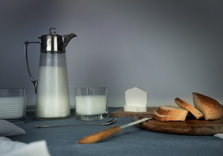 still life. milk jug, candles, tea, eggs, bread rolls cheese on the tableの写真素材