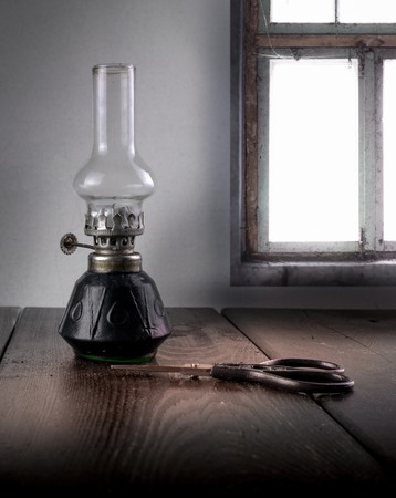kerosene lamp and scissors on a background windowの写真素材