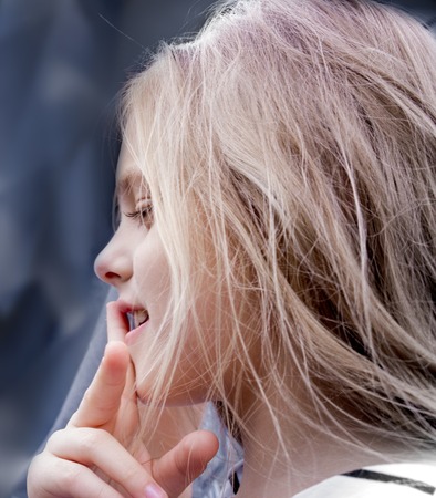 beautiful girl schoolgirl standing, putting a finger to his lips. close-upの写真素材