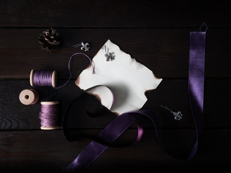 sheet of old paper with purple ribbons and thread on a wooden table.の写真素材