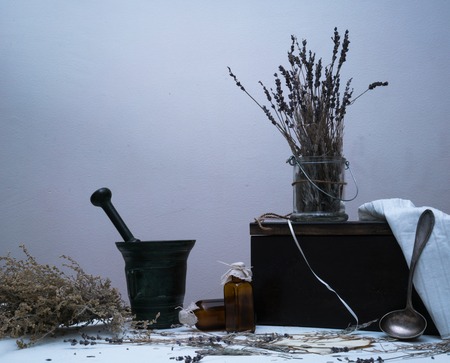medicinal herbs. stupa, bunches of dried wormwood and lavender oil bottle on a table at duskの写真素材