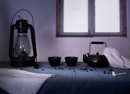lamp and glasses with black tea on a table in the evening on a background of a windowの写真素材
