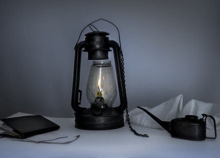 lamp, oiler, a notebook on a table in the twilightの写真素材