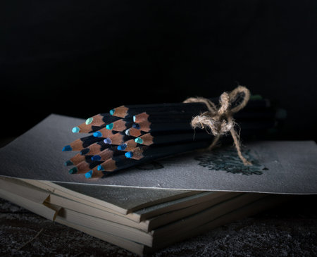 still life. watercolor pencils on the old wooden table. dark background, vintage