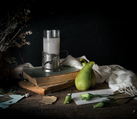 still life, vintage. old books, bouquet of flowers, pear, milk on a wooden table. dark backgroundsの写真素材