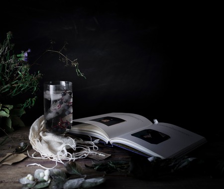 still life, vintage. a glass of mineral water and berries, books, bouquet on  wooden table. dark backgroundsの写真素材