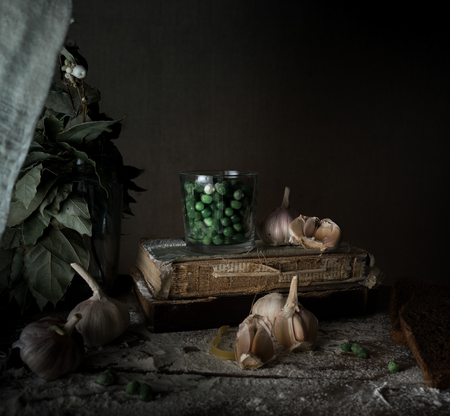 rustic still life, vintage. green peas, old books, garlic, flour on a wooden table. dark backgroundの写真素材