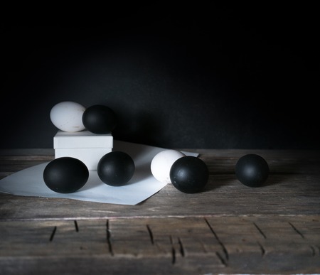 Easter. Easter night. Black and White eggs, feathers on a wooden table. Vintage. Dark backgroundの写真素材
