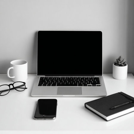 Modern workspace with laptop, smartphone, notebook and coffee cup on white table.