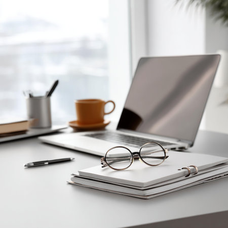 Office workplace with laptop, glasses and coffee cup on white table.