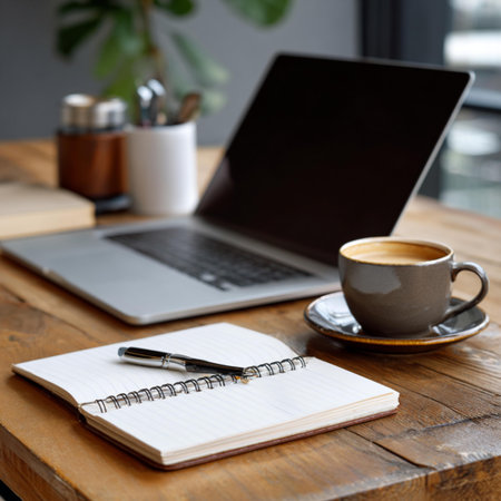 Coffee cup with notebook and laptop on wooden table in cafe