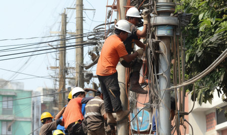 A group of men standing on top of power linesの素材