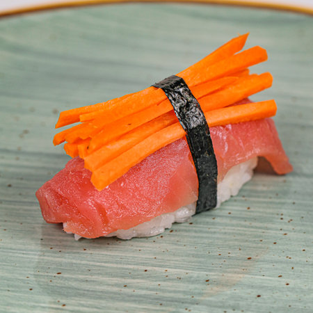 A sushi roll with a vibrant topping of sliced carrots, ready to be enjoyed.の写真素材