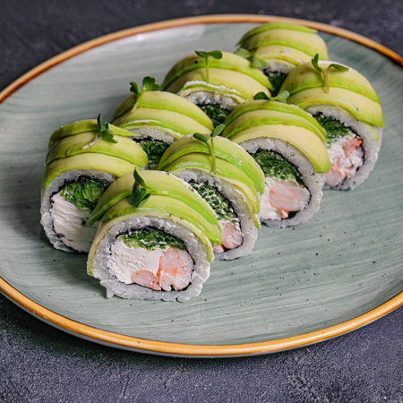 A plate with a selection of different types of sushi rolls, including salmon, tuna, and California rolls, served with soy sauce and wasabi.の写真素材