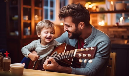 A man passionately plays a guitar while a small boy attentively listens and watches.の素材