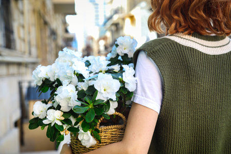 A woman gracefully carrying a basket filled with beautiful white flowers, with plenty of copy space.