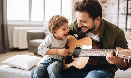 A man sitting and playing a guitar while a little girl watches and listens attentively.の素材