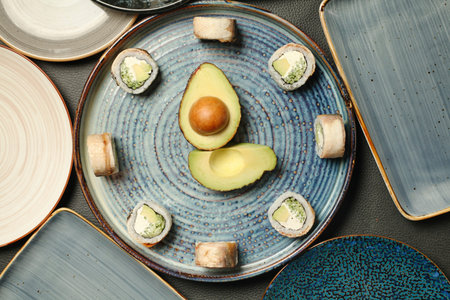 A blue plate with a fresh avocado on top, placed next to several other plates.