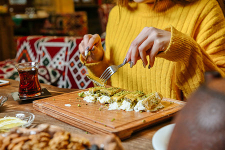 A woman is skillfully slicing and cooking various ingredients on a wooden cutting board.の写真素材